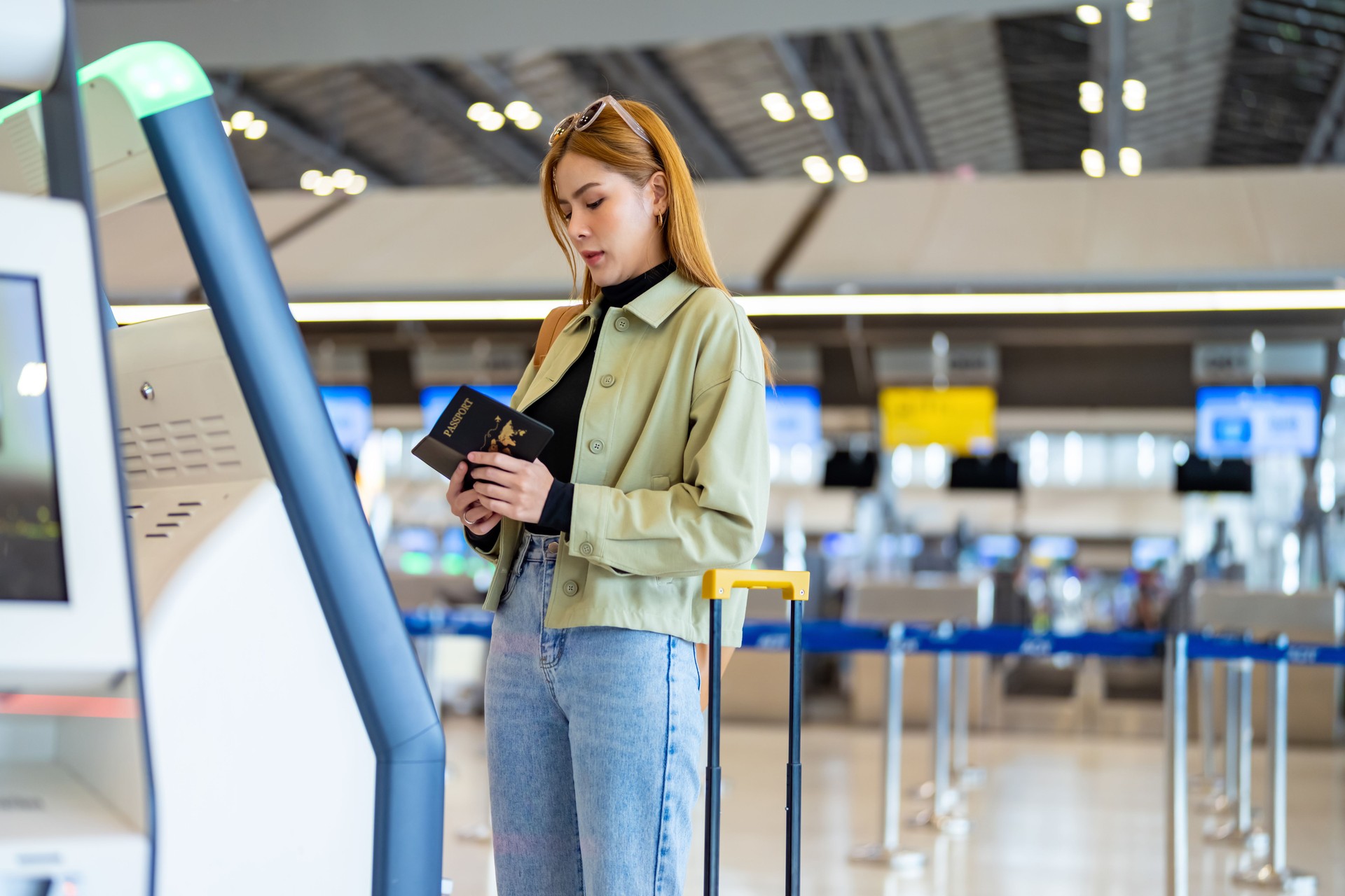 Asian woman using self Check-in kiosk machine at airport terminal.