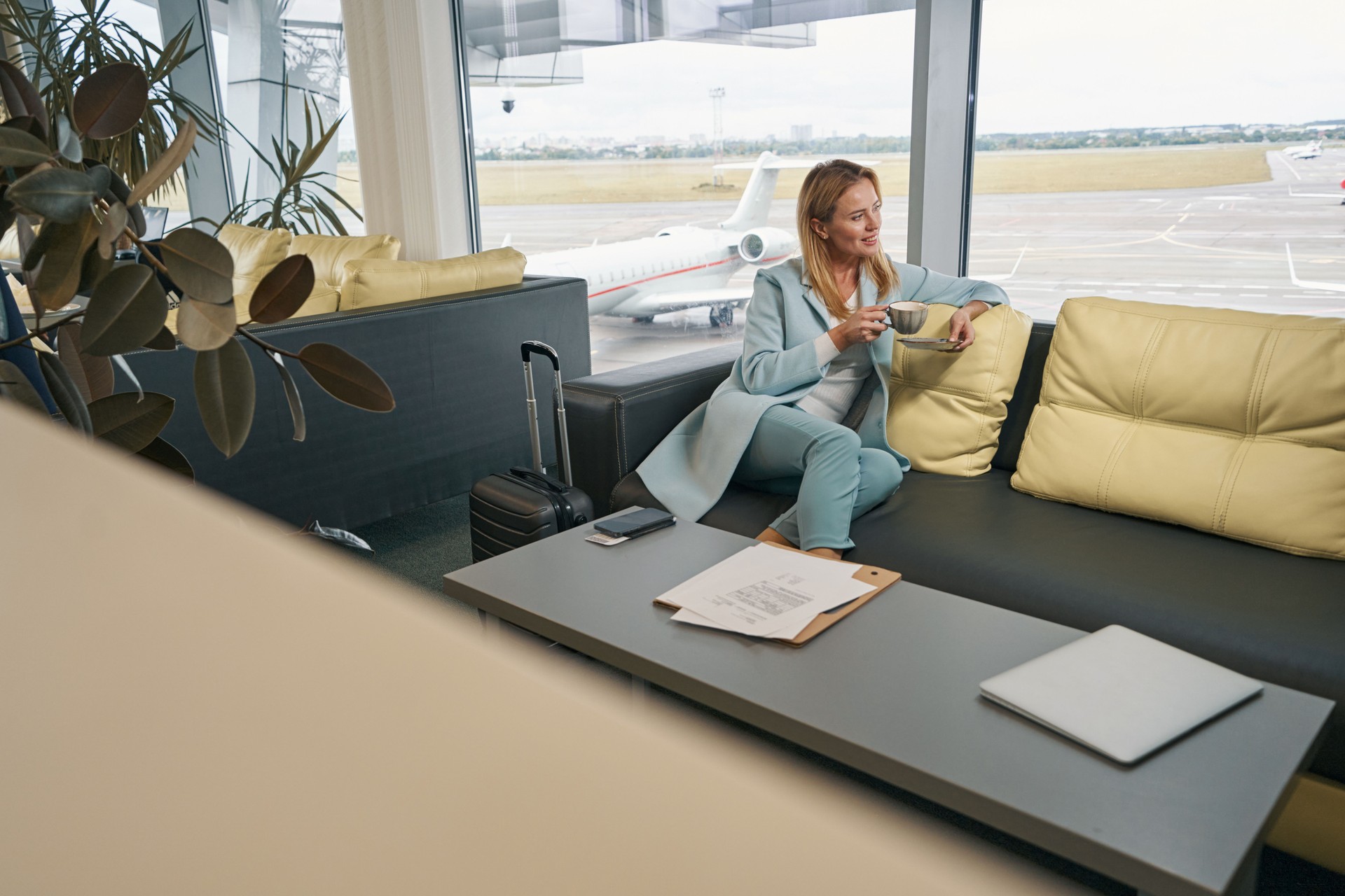 Smiling airline passenger drinking coffee in airport lounge